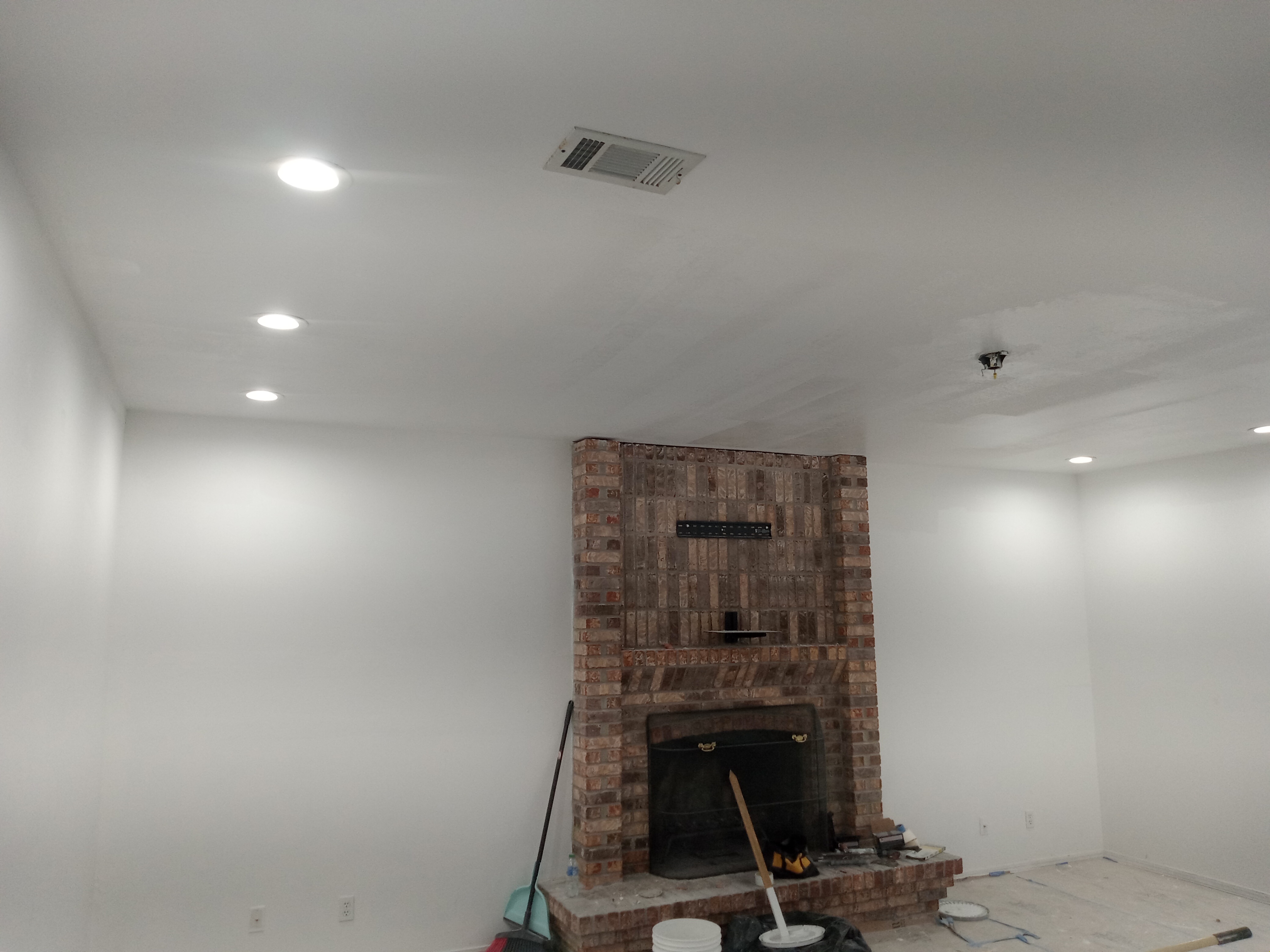 Smooth painted ceiling and walls around a brick fireplace, completed by Time Quality Services